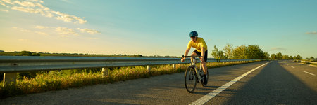 Biker pushing pedals under fading light, asphalt textures and lines leading into distance. Motion blur effect. Banner.の写真素材