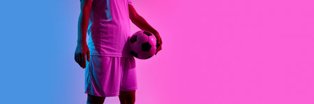 Crop view of female footballer holding ball at waist in white kit under bright neon lights against...