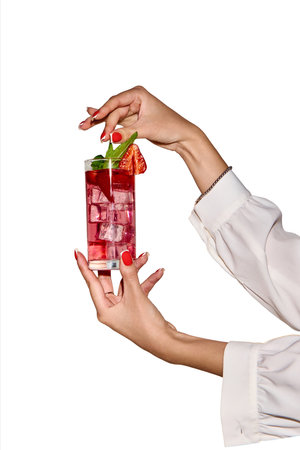 Red refresh. Female hand in blouse holding a strawberry mocktail with mint. Concept of party, celebration.の写真素材