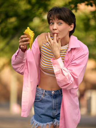 Melting Pleasure. Young woman licks ice cream off her finger after taking a big bite.