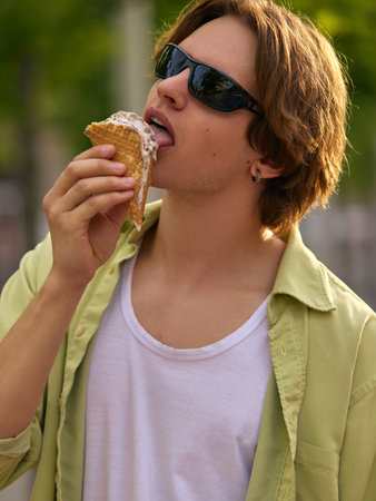 Young man enjoying ice cream cone outdoors on sunny dayの写真素材