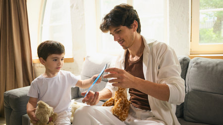 Little boy gives his dad a handmade Fathers Day card in light cozy atmosphereの写真素材