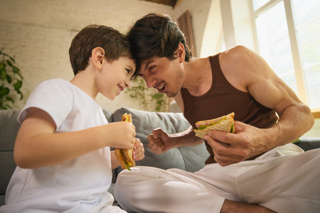 Father and son enjoying casual meal on relaxed Fathers Day celebration indoorsの写真素材