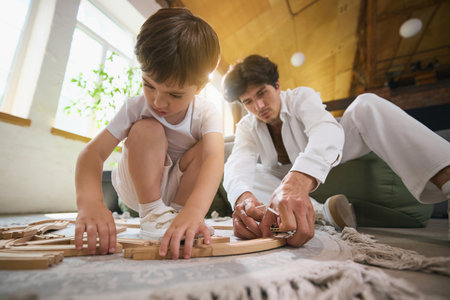 Father and son building with blocks together on floor in sunny roomの写真素材
