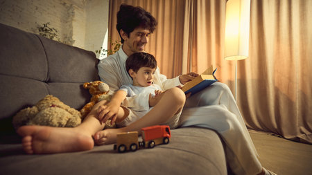 Father reading bedtime story to son on cozy living room sofaの写真素材