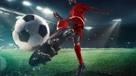 Soccer player strikes ball on 3D field under stadium lights in close-up actionの写真素材