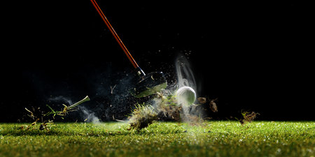 Close-up of a golf club hitting the ball with dirt and grass flyingの写真素材