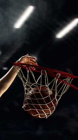 Basketball dunk with player hand pushing ball through hoopの写真素材
