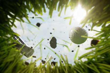 Golf ball mid-air with grass and dirt flying, shot from low ground perspectiveの写真素材