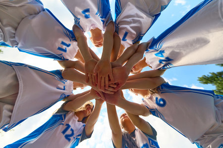 Women basketball team gathering in a motivational huddle in uniform outside