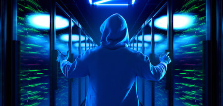 Hooded man standing with arms raised in server corridorの写真素材