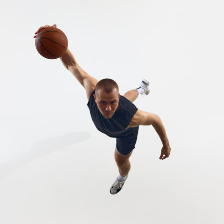 Athletic man executing dynamic basketball slam dunk in mid-air
