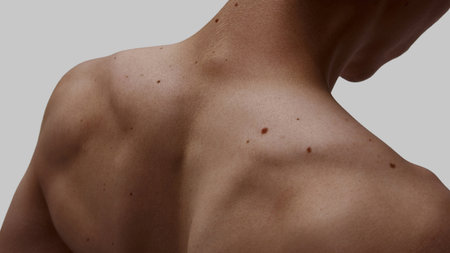 Close-up of male upper back with visible moles and muscles on neutral backgroundの写真素材