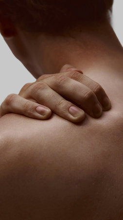 Male hand touching shoulder with subtle tension and vulnerability