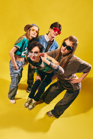 Stylish Gen Z friends in streetwear posing on bright yellow background with confident attitude