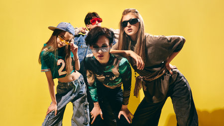 Confident Gen Z group in trendy streetwear looking at camera on bright yellow backdrop