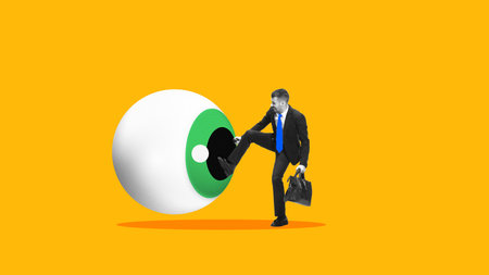 Contemporary collage. Businessman kicking giant eyeball on yellow backgroundの写真素材