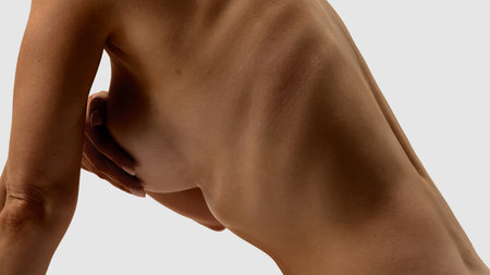 Female torso side view with hand covering breast and visible rib structure