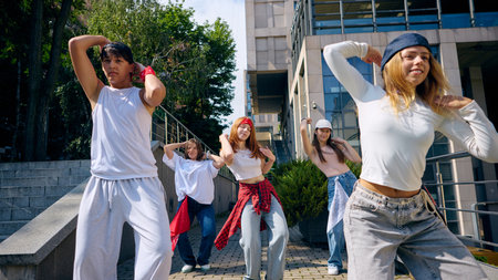 Street dance group performing synchronized choreography outdoors with joyful energyの写真素材