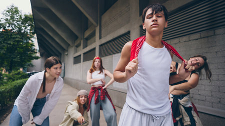 Male street dancer in white tank top posing with attitude while crew supportsの写真素材