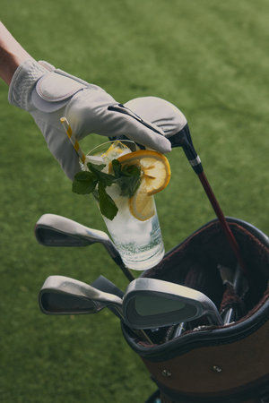 Golf glove holding refreshing cocktail with mint and lemon