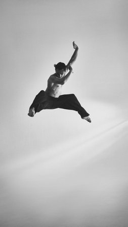 Male performer leaping with sharp arms expressive intensity and dramatic focusの写真素材