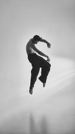 Male dancer suspended midair curled posture with introspective emotional mood