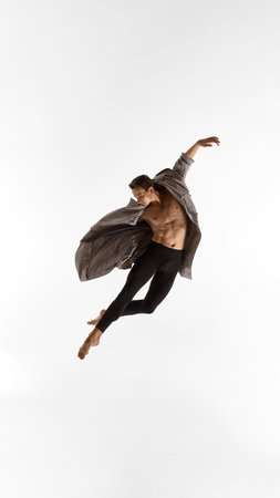 Male performer suspended midair in coat with curved posture and expressive emotionの写真素材