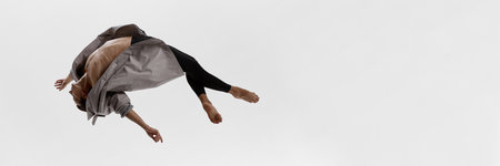 Male dancer twisting midair in coat with curved torso and emotional abstraction. Bannerの写真素材