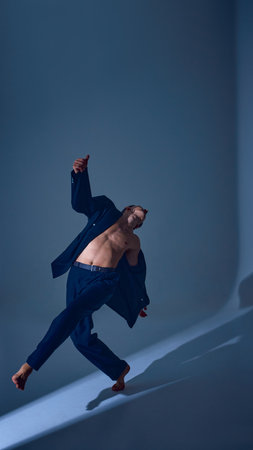 Male performer leaning sideways in suit with graceful motion and emotional introspectionの写真素材