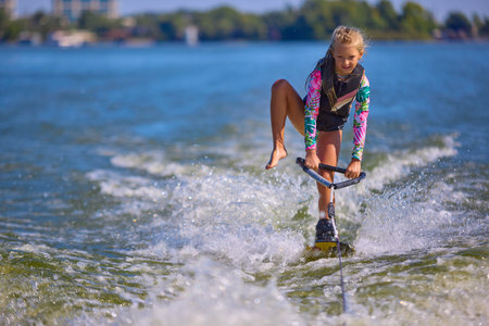 Young girl wakeboarder balancing with one leg over water wavesの写真素材