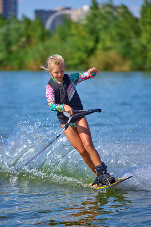 Girl wakeboarder leaning into water spray with strength and controlの写真素材