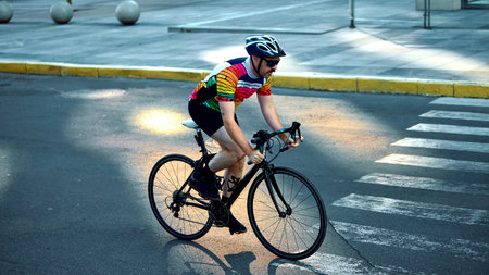 Cyclist riding road bike on urban street crosswalk with focus and energyの写真素材