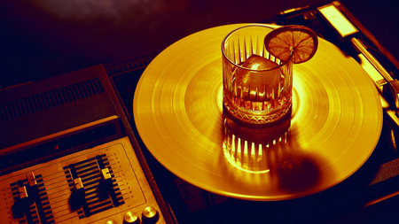 Cocktail with lemon slice served on glowing golden vinyl record