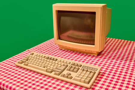 Retro beige computer monitor and keyboard on checkered tableの写真素材