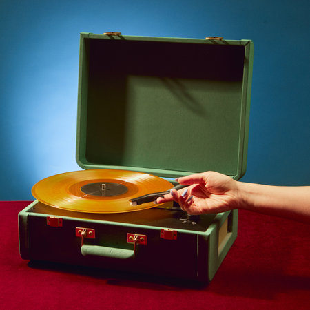 Female hand gently placing needle on golden vinyl with nostalgic emotion