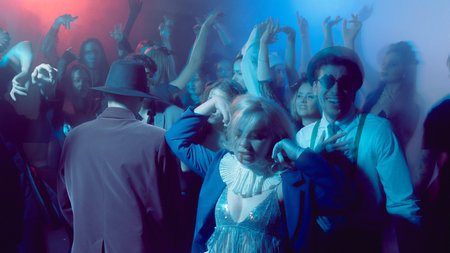 Group of young people dancing in Halloween costumes under club lights