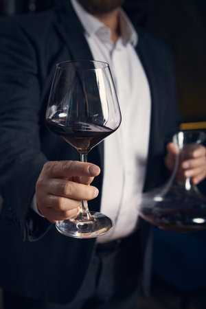 Sommelier offering glass of red wine with calm confidence
