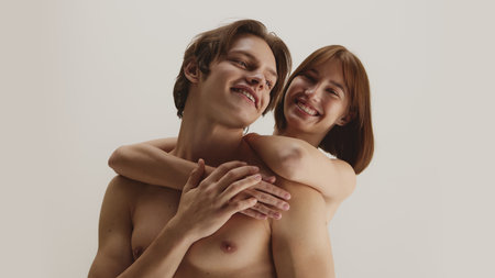 Joyful woman embracing smiling man from behind with healthy glowing skinの写真素材