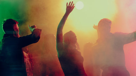 Christmas party woman dancing confidently in spotlight amid vibrant crowdの写真素材