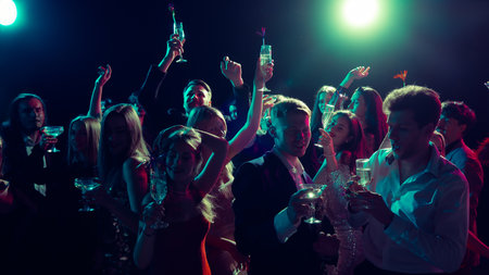 New Year party toast with champagne glasses under neon lightsの写真素材
