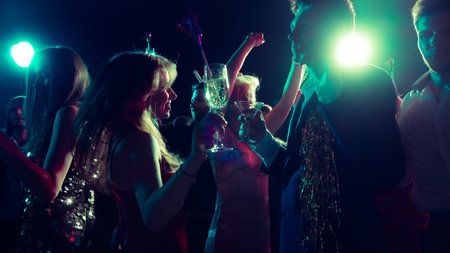 Joyful Christmas night with friends dancing and clinking glassesの写真素材