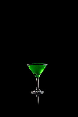 Green cocktail in martini glass on black reflective surfaceの写真素材