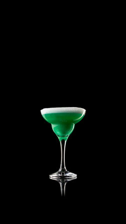 Minimal green cocktail in coupe glass on black reflective surfaceの写真素材