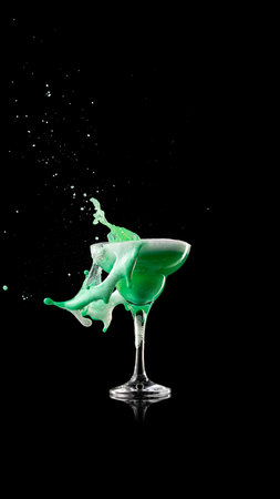 Green creamy cocktail splash in coupe glass with foam motionの写真素材