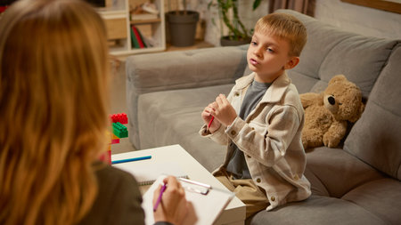 Boy explaining creative idea with toy blocks during psychology counseling sessionの写真素材
