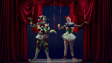 Puppets of stage. Mime and ballerina posing as marionettes under red curtains.