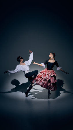 Ballet dancers in elegant pose under dramatic stage light.