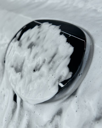 Close-up of car logo covered in foam during washing processの写真素材