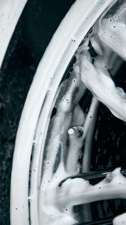 Detail shot of wheel covered with foam during car washingの写真素材